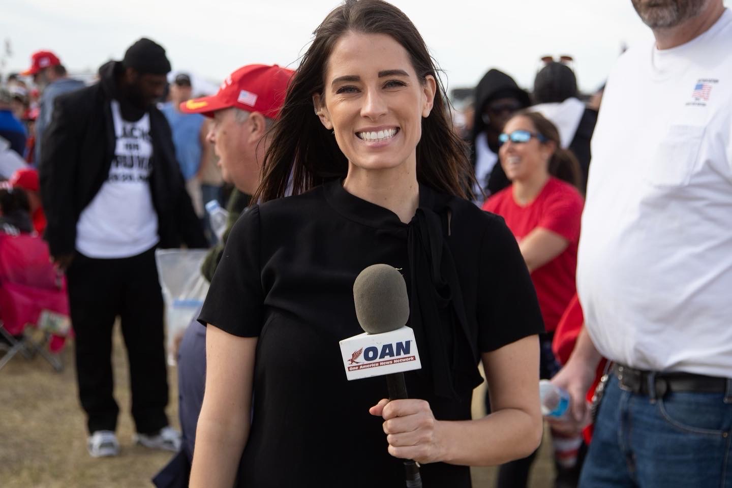 A reporter standing on a field with mic in hand